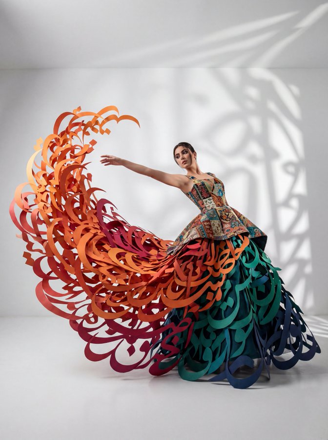 A full-body wide-angle studio fashion scene featuring a dynamic subject in a conceptual avant-garde gown with a fitted patchwork tapestry bodice and a massive matte-paper skirt made of 3D Persian calligraphy strokes swept into a windblown vortex.