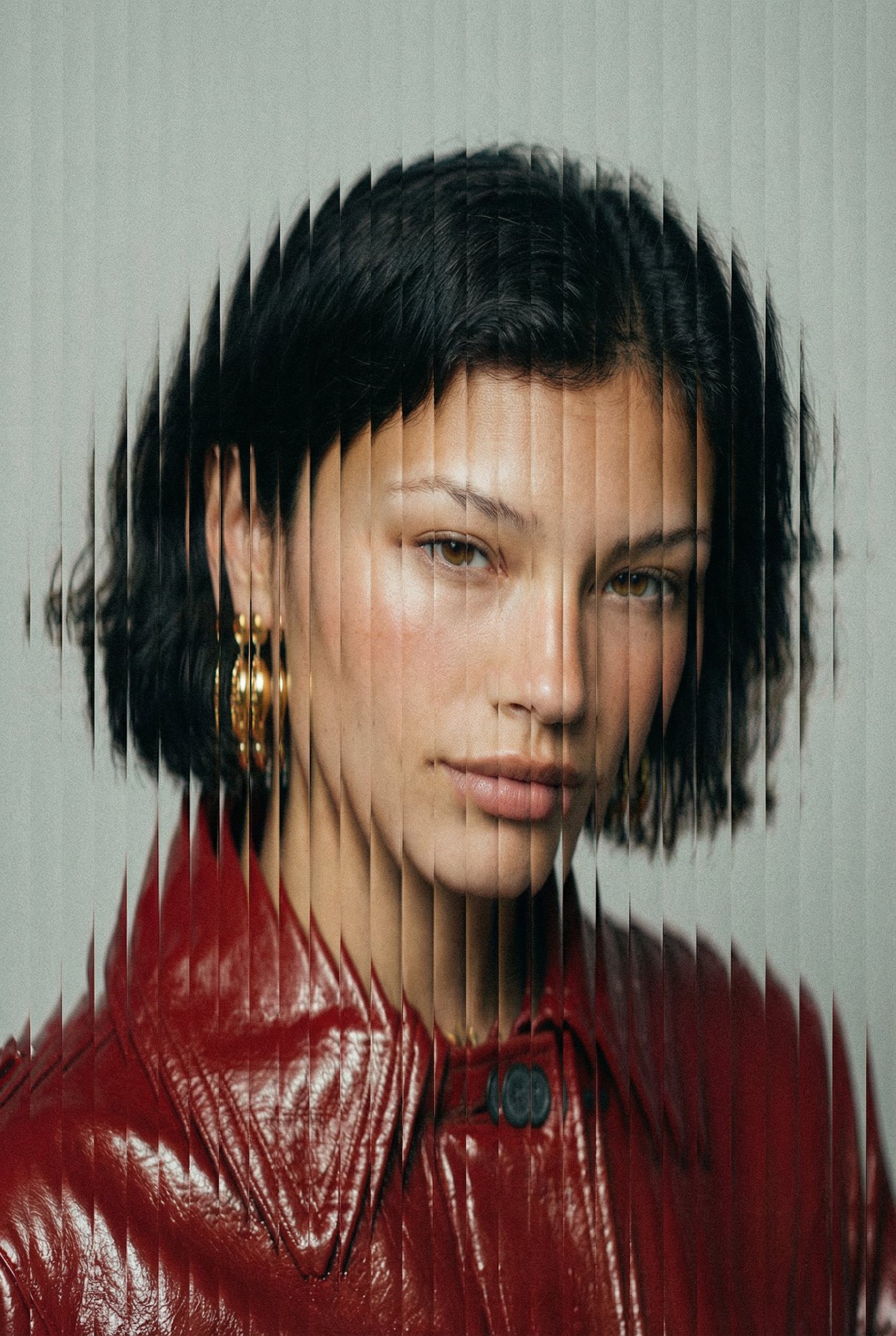 A high-fashion, tight face-centered portrait with vertical slit-scan glitch slicing, analog-style grain, and a muted neutral palette with a deep red accent. Shot straight-on with an 85mm portrait lens and shallow depth of field focused on the eyes.